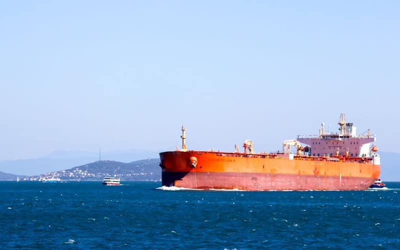 A large cargo ship navigating the open blue sea under a clear sky, showcasing maritime transport.