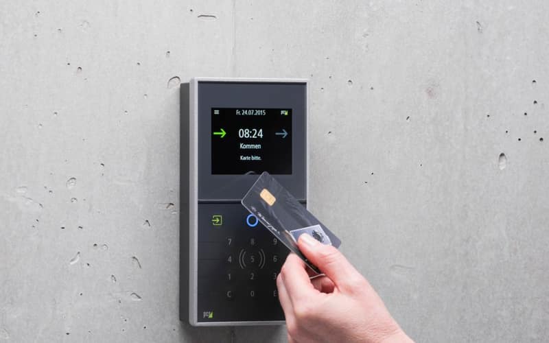 A businessman uses a secure card reader access system against a concrete wall.