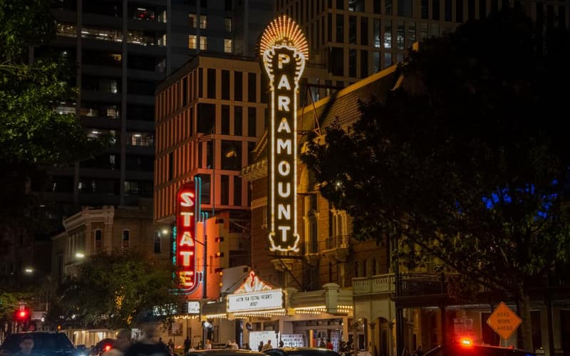 Bustling city street scene at Paramount Theater in Austin, TX during night.
