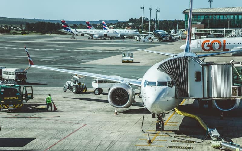 A scenic view of airplanes at an airport runway during a busy day, ready for boarding.