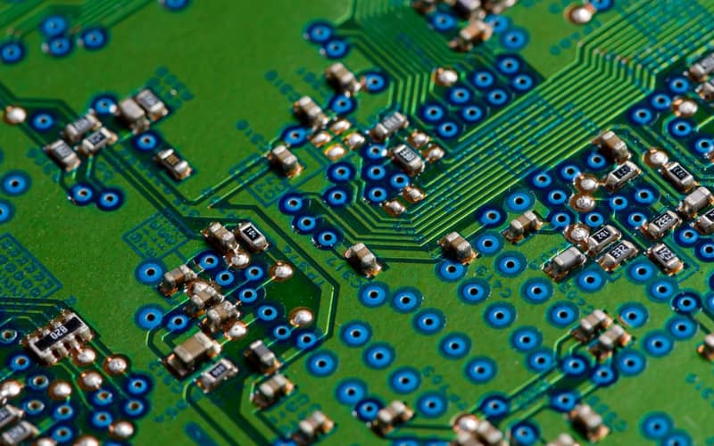 Immagine dettagliata di un circuito stampato verde che mostra componenti elettronici per uso tecnologico.