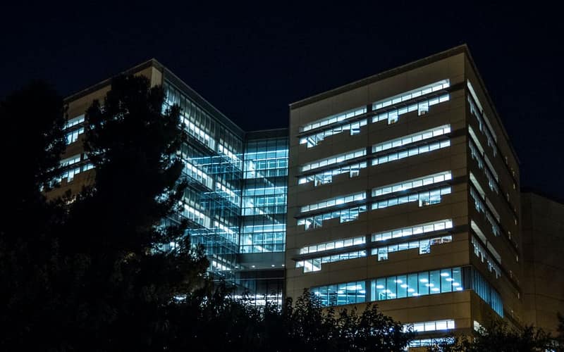 A contemporary office building lit up against the night sky, showcasing its modern architecture.