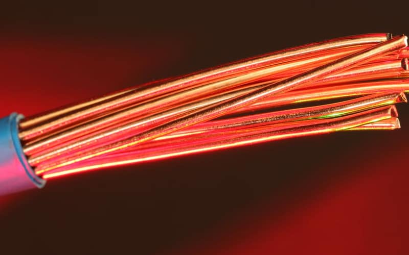Detailed image of copper wires illuminated by red light, highlighting texture and color.
