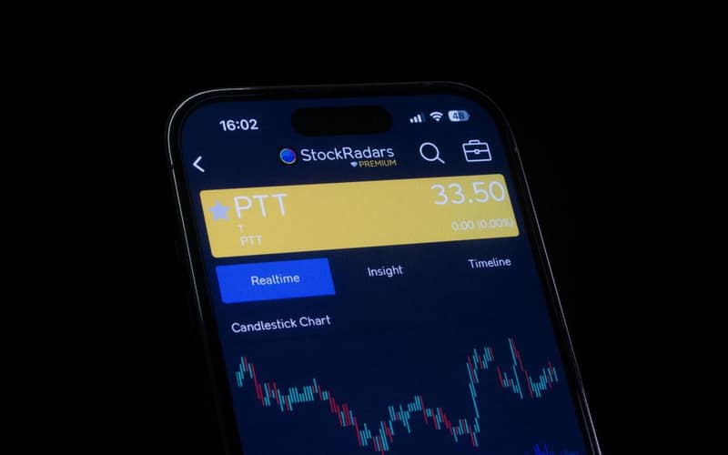 Close-up of a smartphone screen displaying a stock trading app with candlestick charts, showing real-time stock data.