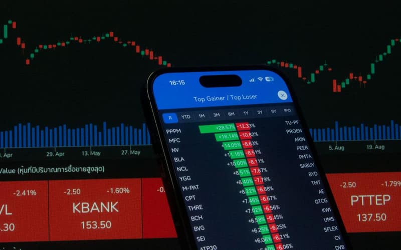 Smartphone with stock market data in front of financial chart.