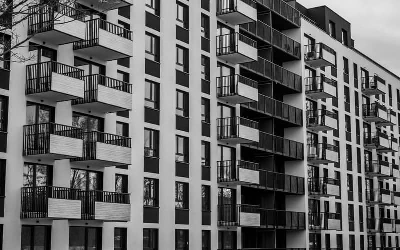 Foto in bianco e nero di un moderno edificio di appartamenti con numerosi balconi.