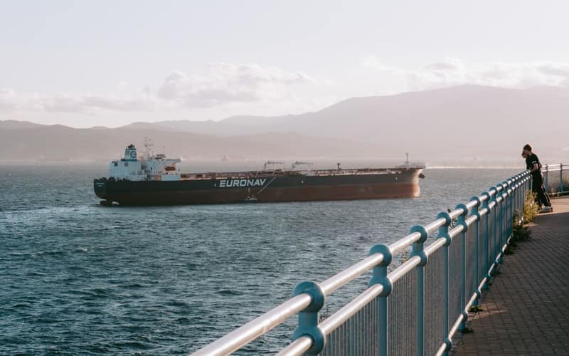 Cargo ship navigates the Gibraltar Strait as the sun sets, scenic view.
