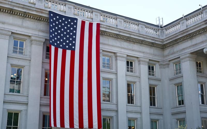 A large American flag hangs on a historic government building in Washington, D.C., showcasing national pride.