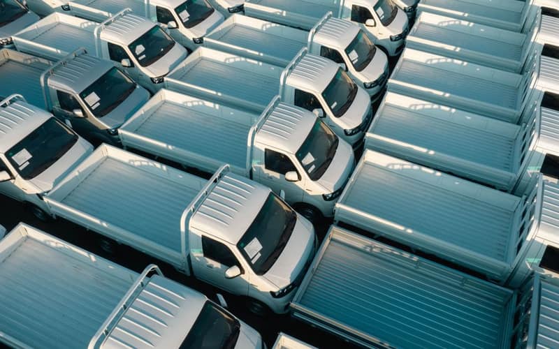 Aerial view of white pickup trucks parked in rows, emphasizing symmetry and industrial style.