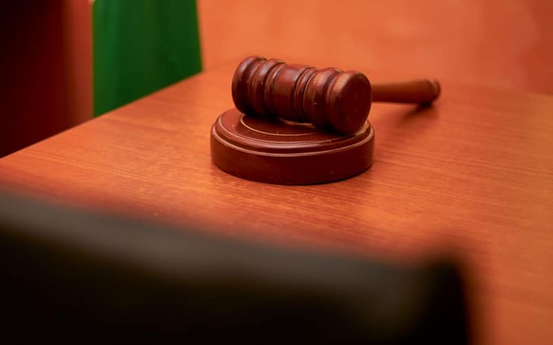 A close-up of a gavel on a courtroom desk representing law and justice.