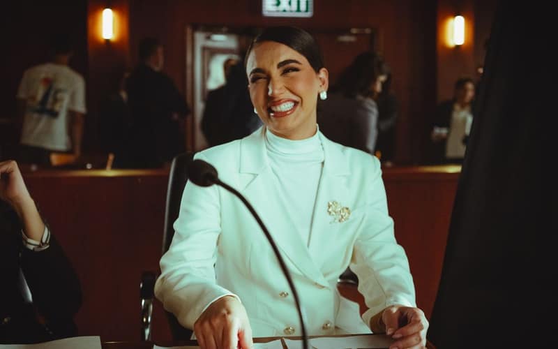 Smiling woman in white suit in a courtroom, conveying professionalism and confidence.