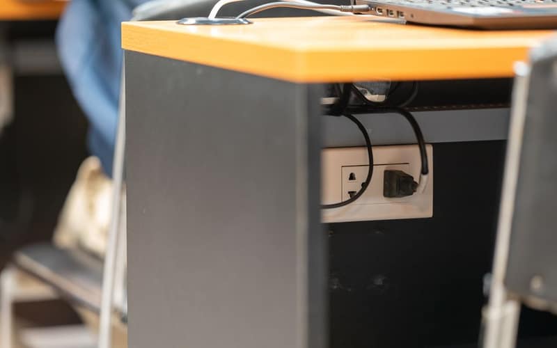 A clean office workspace featuring a desk, laptop, and hidden power cord management.