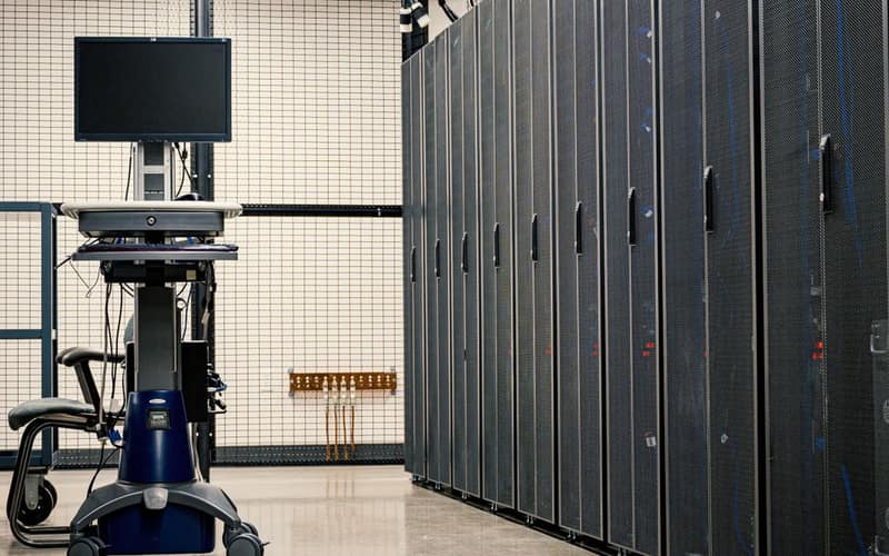 Contemporary computer on support between telecommunication racks and cabinets in modern data center