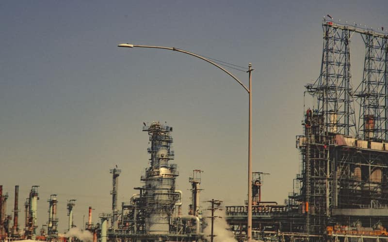 A large industrial refinery with pipes and towers under a clear blue sky during the day.