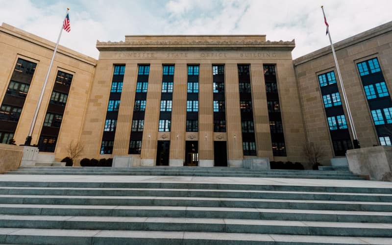 From below of Federal Reserve building exterior against USA flags and staircase under cloudy sky in town