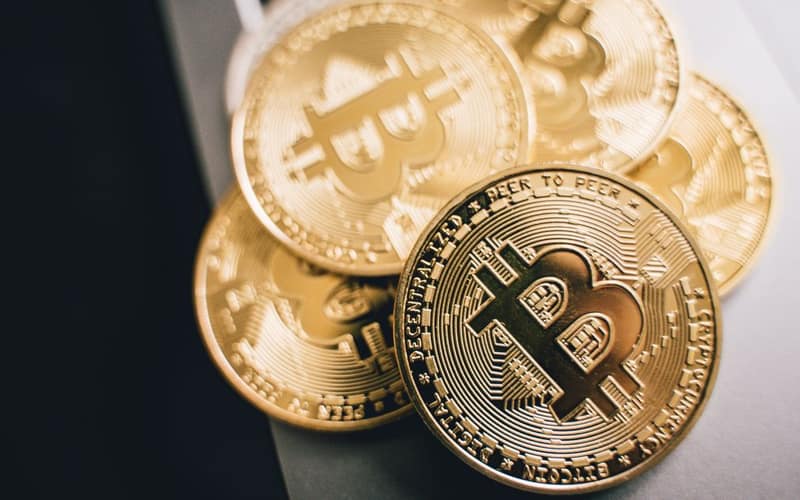 Close-up of golden Bitcoin coins on a laptop keyboard, symbolizing cryptocurrency investment.