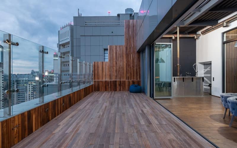 Ampia terrazza vuota con pavimento e pareti in legno, in un appartamento moderno in una giornata nuvolosa