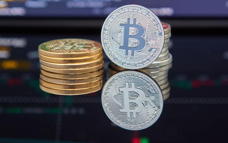 Bitcoin coins stacked in front of cryptocurrency trading chart reflecting market trends.