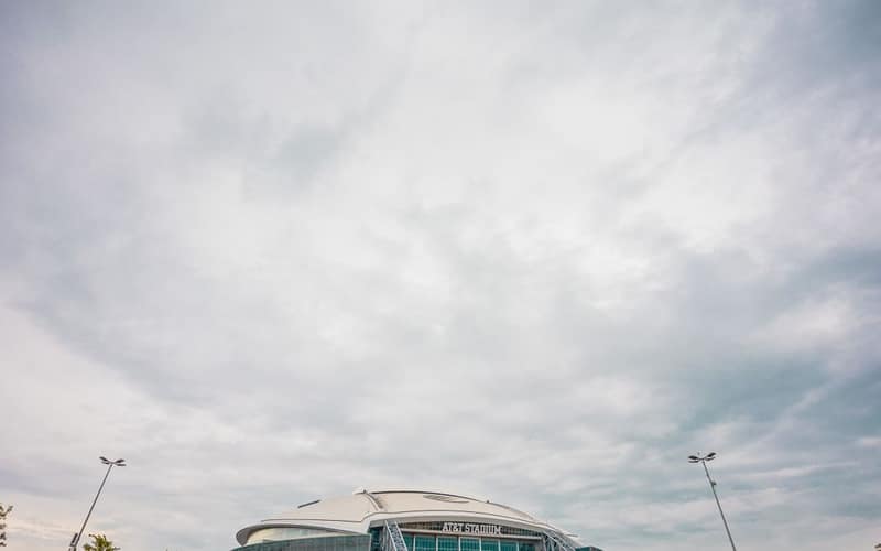 Wide-angle view of AT&T Stadium under dramatic clouds highlighting modern architectural design.