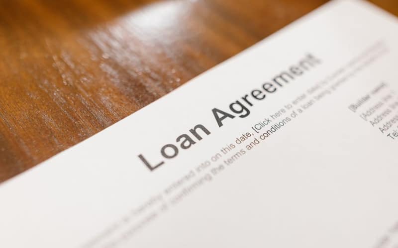 Detailed loan agreement document close-up on a wooden table representing legal and financial concepts.
