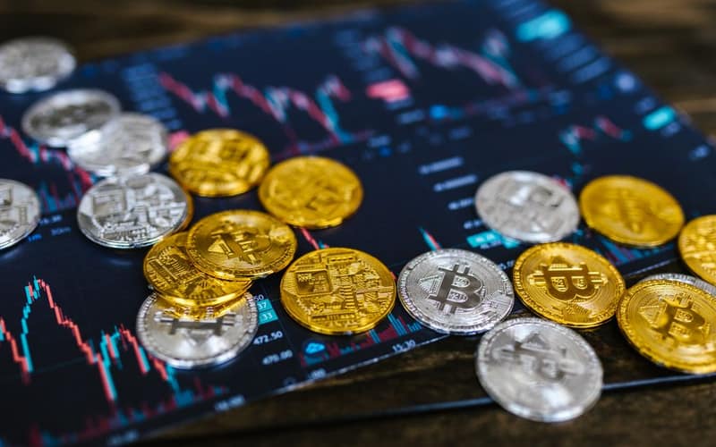 Gold and silver Bitcoin coins on financial graph, symbolizing cryptocurrency trading and digital currency wealth.