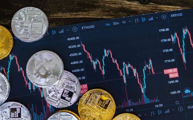 Close-up of gold and silver cryptocurrency coins on a digital trading chart.