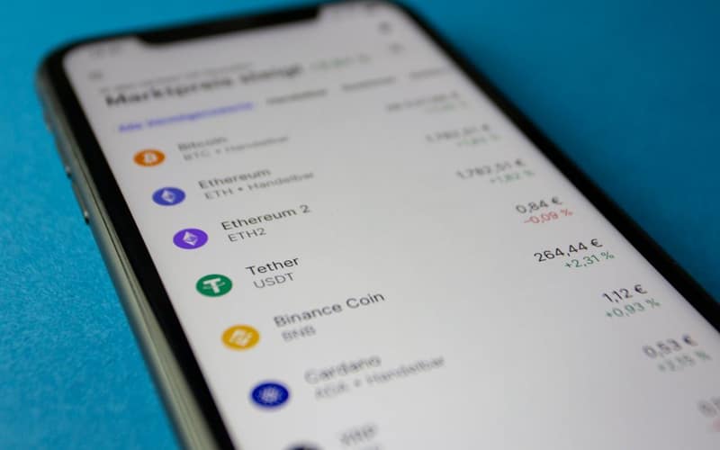 Close-up photo of a smartphone displaying cryptocurrency market data with price listings.